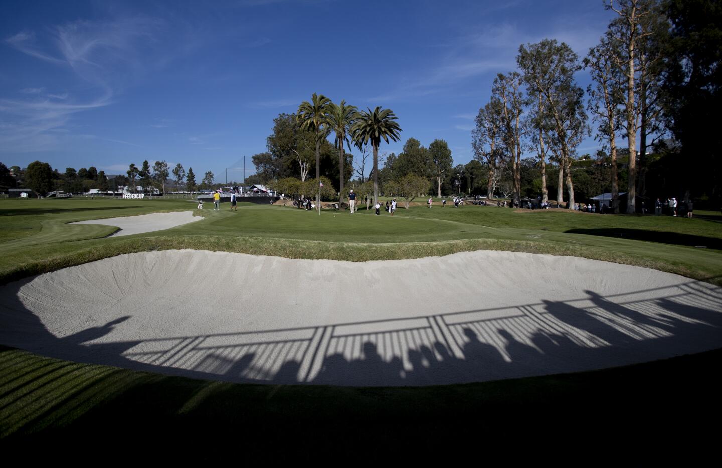 Shadows of fans in the gallery stretch across one of the bunkers on the 10th hole during the first round of the Genesis Invitational at Riviera Country Club on Feb. 13, 2020.