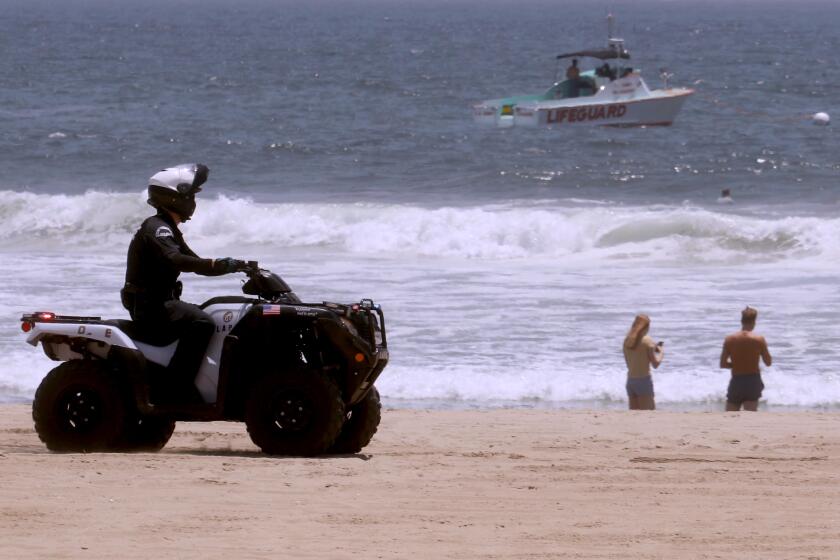 VENICE, CA - JULY 05, 2020 - - A police officer and a lifeguard boat comb the shoreline in Venice Beach on July 5, 2020. Even though the beach was closed this weekend a few still made their way to the shoreline. In what officials have described as an "alarming" increase, hospitalizations of patients with confirmed coronavirus infections in Los Angeles County have jumped 41% in the last three weeks. On Friday, there were 1,947 patients in L.A. County hospitals with confirmed coronavirus infections; seven days earlier, there were 1,717; the week before that, there were 1,426; and the week prior to that, there were 1,383. (Genaro Molina / Los Angeles Times)