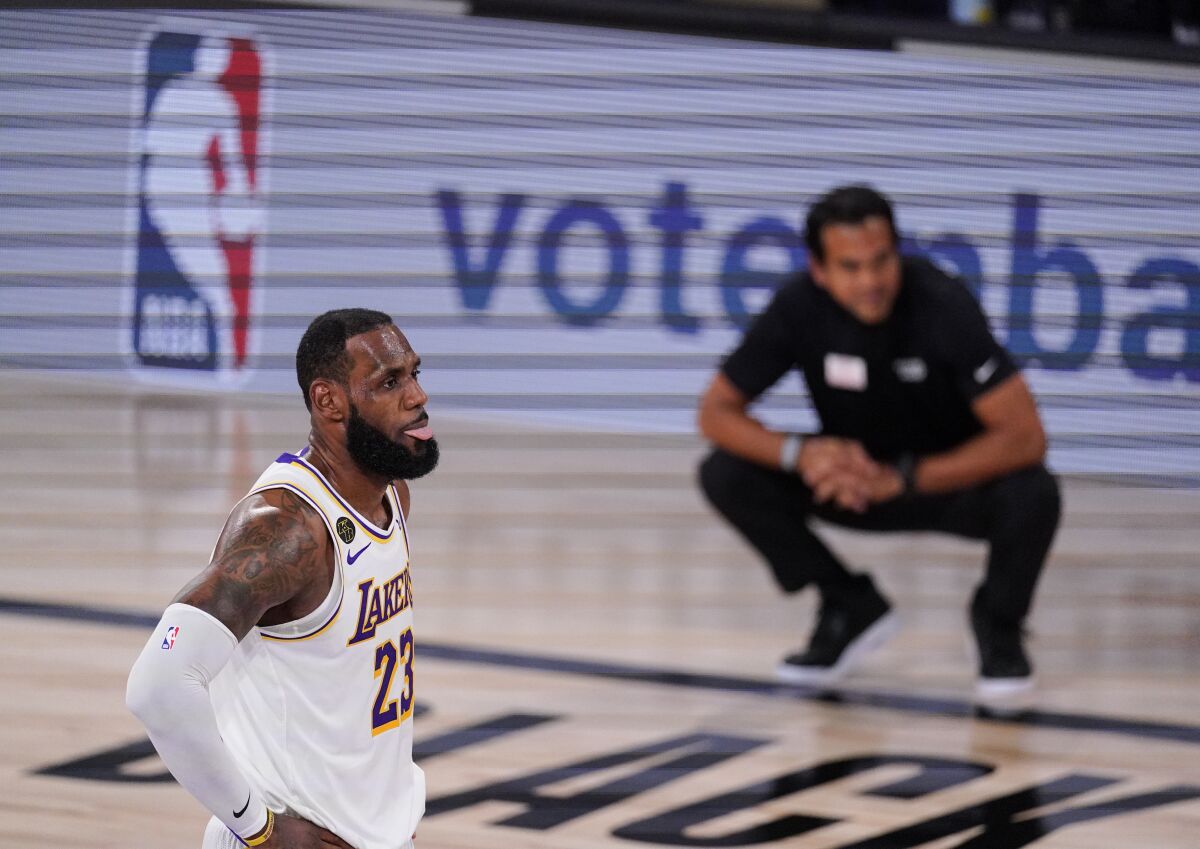 Los Angeles Lakers' LeBron James (23) looks on with Miami Heat's head coach Erik Spoelstra in the back ground during the first half in Game 3 of basketball's NBA Finals, Sunday, Oct. 4, 2020, in Lake Buena Vista, Fla. (AP Photo/Mark J. Terrill)