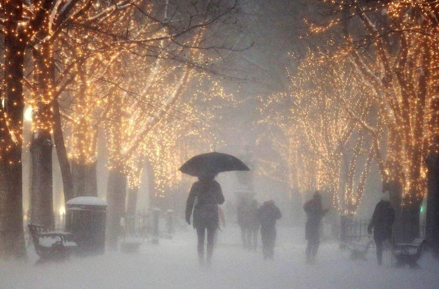 People walk through the Commonwealth Avenue Mall during a winter storm in Boston.