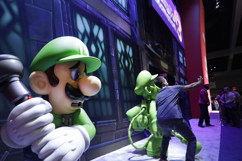 LOS ANGELES, CA -- JUNE 11, 2019: An attendee takes a picture in front of "Luigi's Mansion 3" during E3 at the Los Angeles Convention Center. (Myung J. Chun / Los Angeles Times)