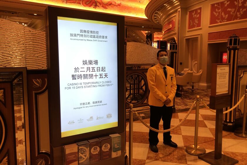 A security guard blocks the entrance to the Venetian Macau's gaming floor to comply with the territory's 15-day shutdown of casinos to stop the spread of the coronavirus.