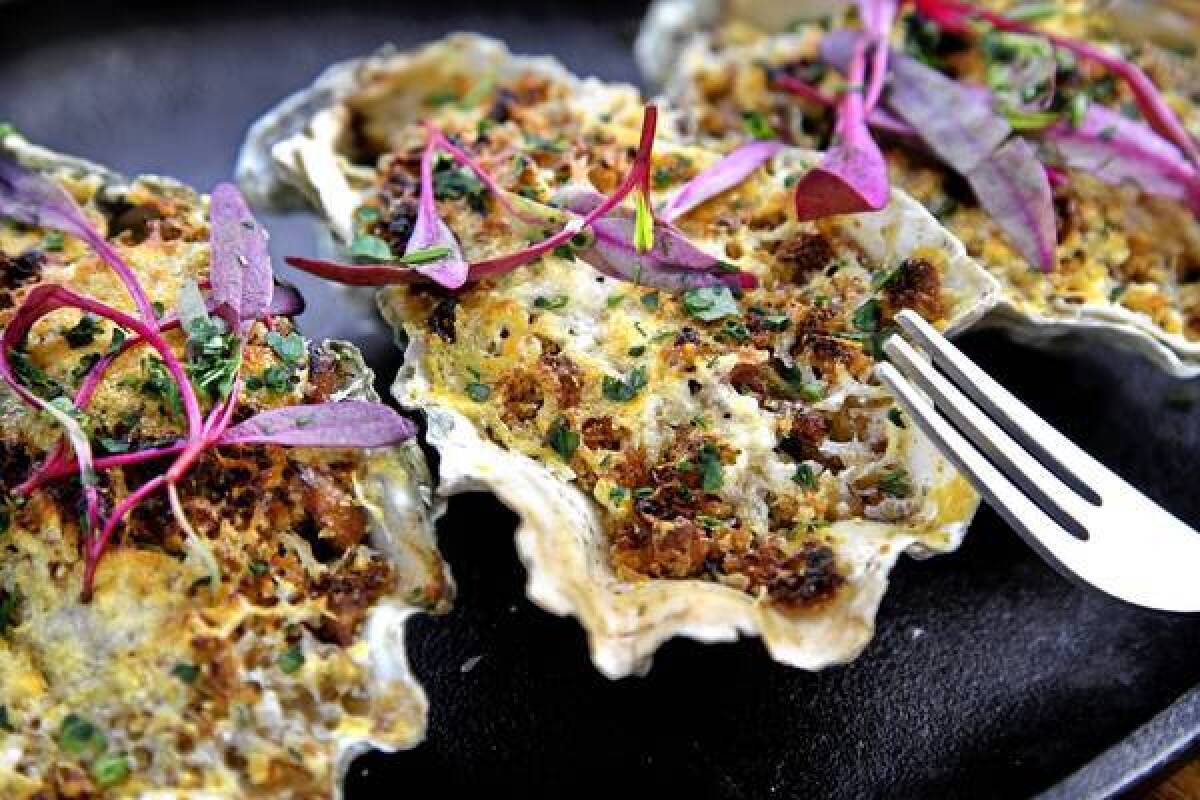 Grilled oysters with caramelized shallots, seared hedgehog mushrooms, dry sherry, bread crumbs and Parmesan, topped with baby beet micro greens, at L&E Oyster Bar.