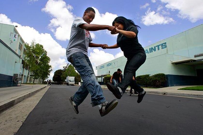 Mykel Polk, 16, and Areli Martinez, 18, practice a skateboard jump together during lunch on Saint Street, a road that cuts through the 25-acre campus. The schools disjointed layout has made it hard over the years to keep the campus free of vandalism. It also made it easier for students to ditch classes. Charter-school operator Green Dot clamped down this year with a heavy security presence and strict rules, which limited student opportunities for blowing off steam during breaks. But Green Dot has loosened up a bit, allowing skateboarding, pickup soccer games and other activities in selected areas.