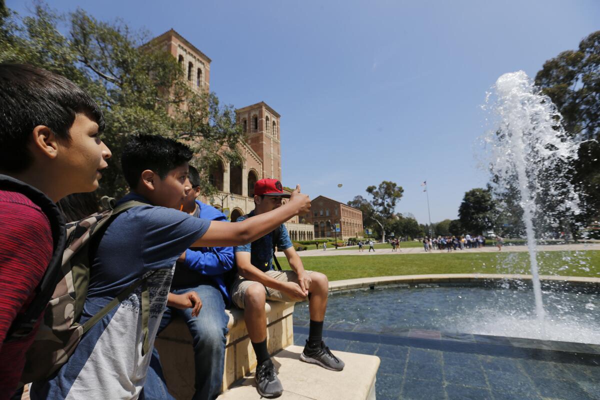 Jesus Perez, 13, center, an 8th grader from Mountain View Middle School in Moreno Valley, tosses a coin in a fountain for good luck as he and his classmates visit UCLA.
