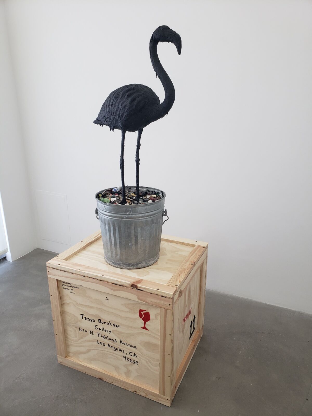A flamingo in a pot on a wood box