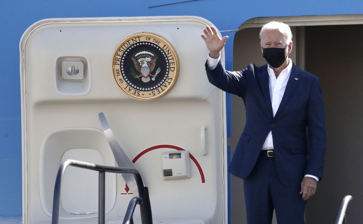 President Biden stands at the door of a plane.