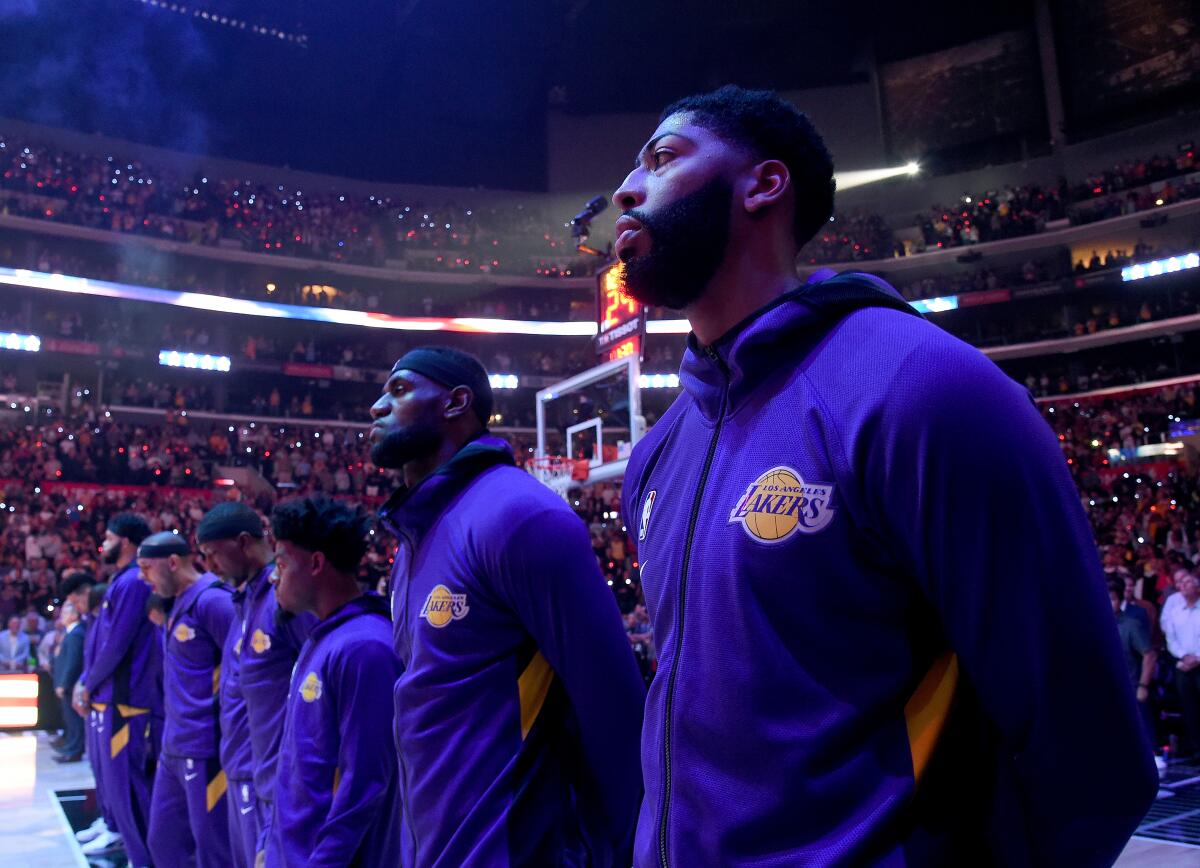 Lakers forwards Anthony Davis, right, and LeBron James listen to the national anthem before a game against the Clippers.