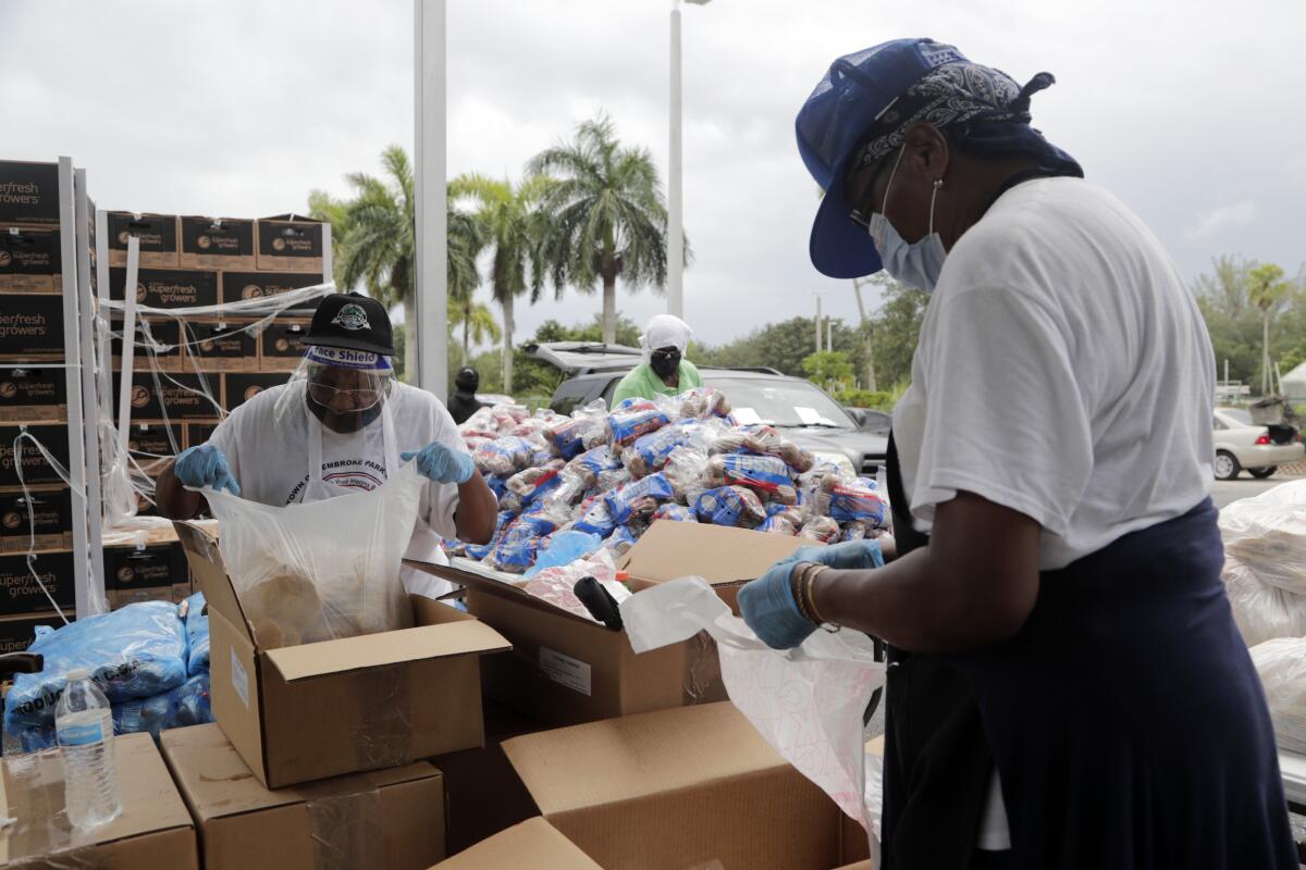 Volunteers load food from cardboard boxes into bags at a food distribution site in Pembroke Park, Florida