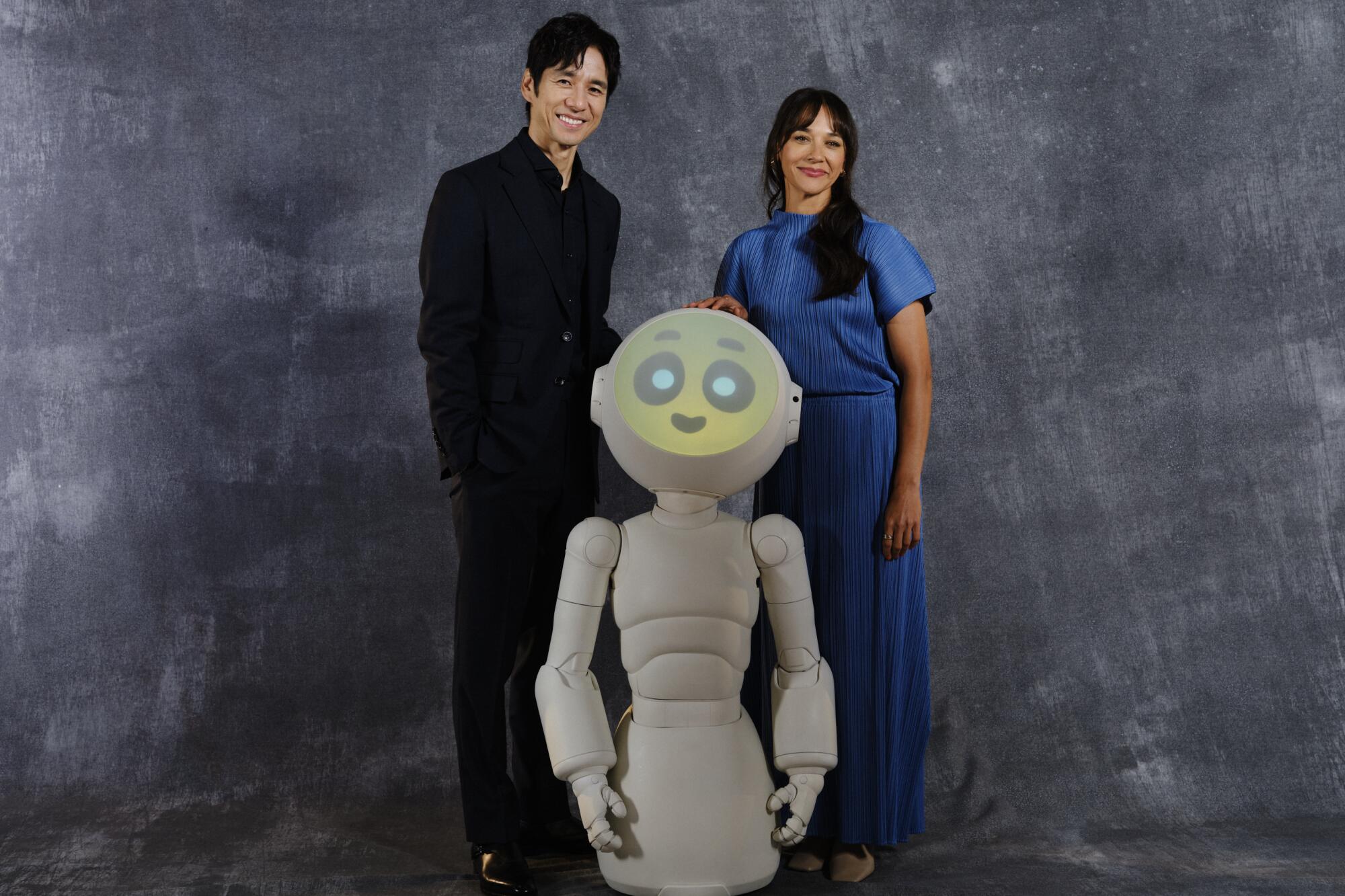 Hidetoshi Nishijima and Rashida Jones posing with a humanoid robot.
