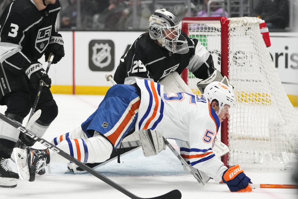 Edmonton's Dylan Holloway falls to the ice as he chases the puck past Kings goaltender Pheonix Copley.