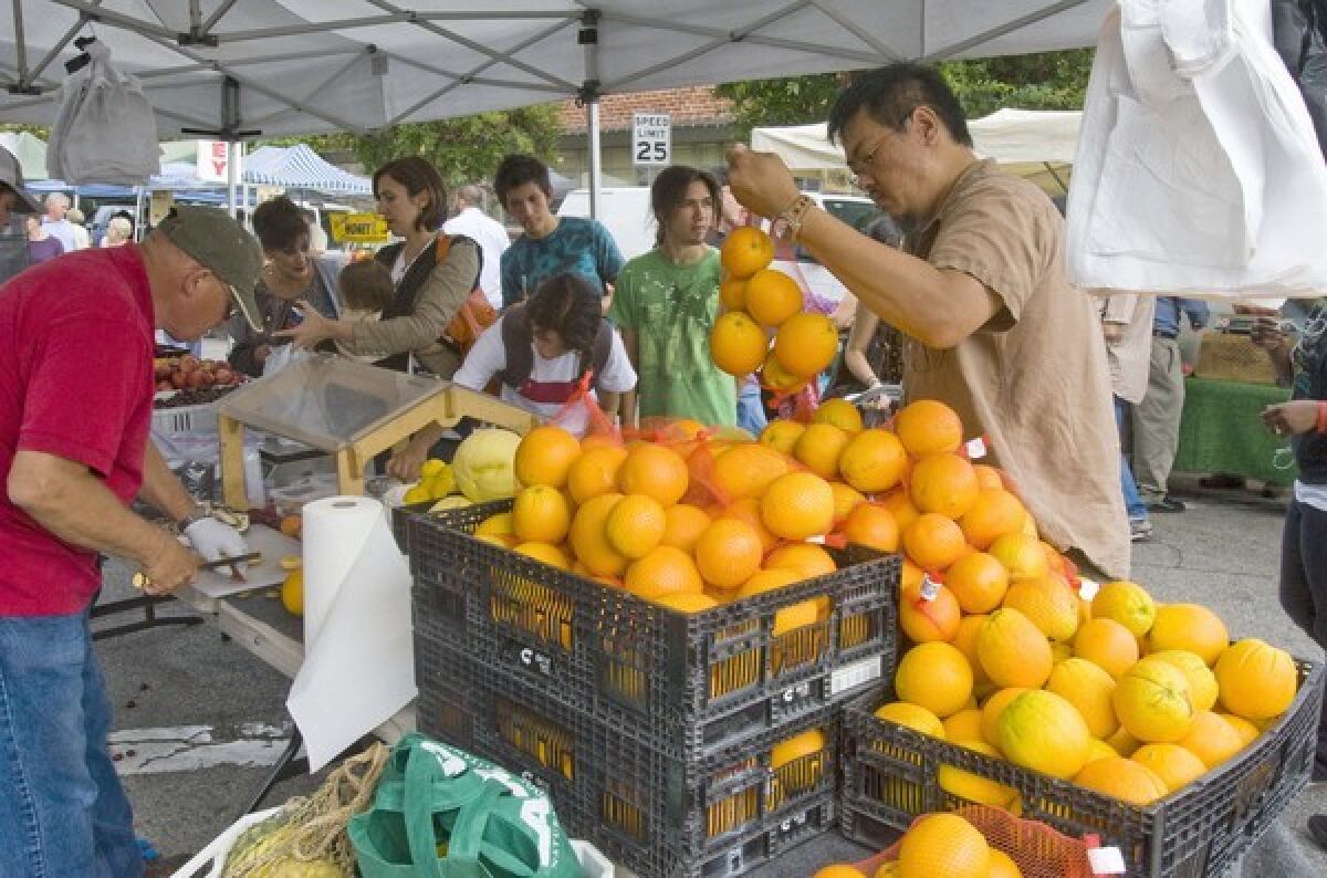 A customer at the Etheridge Farms stand at the South Pasadena farmers market picks out navel oranges grown in Dinuba. RELATED: Farmers market flap in South Pasadena as new manager shakes things up