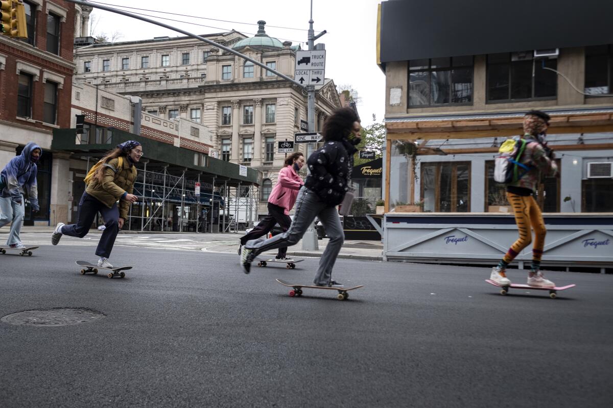Five young women on skateboards in a city street.