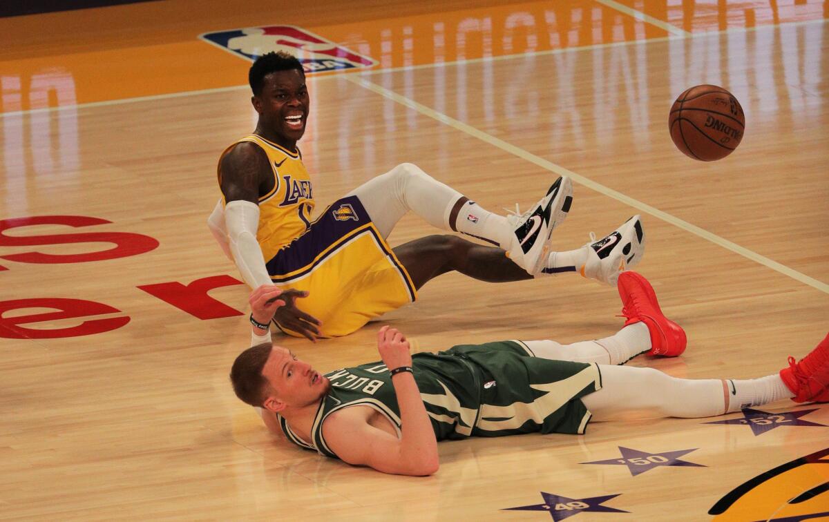 Dennis Schroder is sitting and Milwaukee's Donte DiVincenzo is lying on the court.