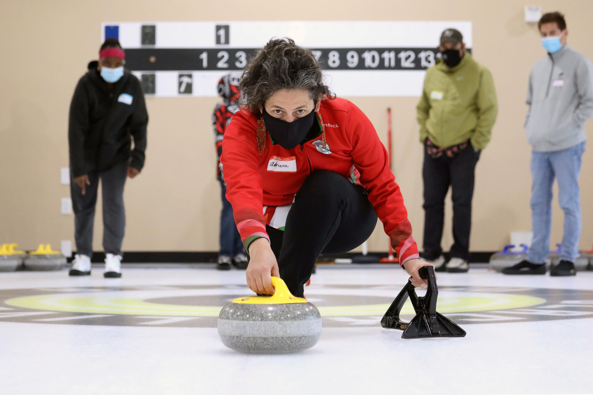 Instructor Adriana Camarena, who is a member of the Mexican curling team, demonstrates to students how to deliver a stone