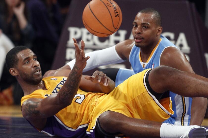 Lakers forward Shawne Williams passes the ball as Denver Nuggets guard Randy Foye looks for the steal.