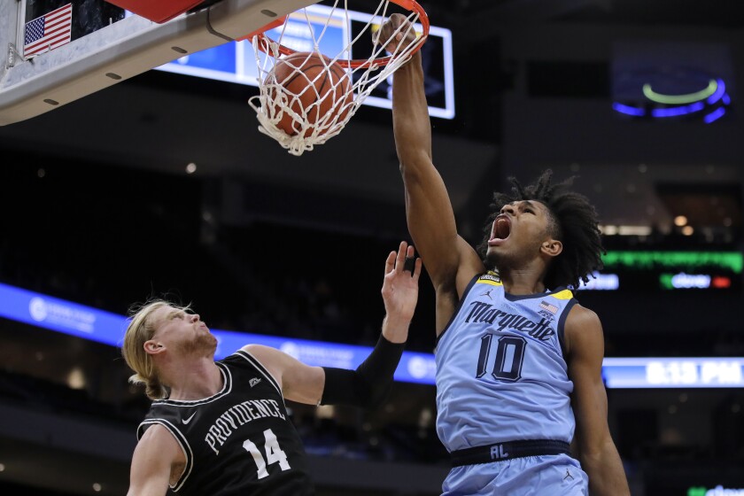 Marquette's Justin Lewis (10) dunks over Providence's Noah Horchler (14) during the first half of an NCAA college basketball game Tuesday, Jan. 4, 2022, in Milwaukee. (AP Photo/Aaron Gash)