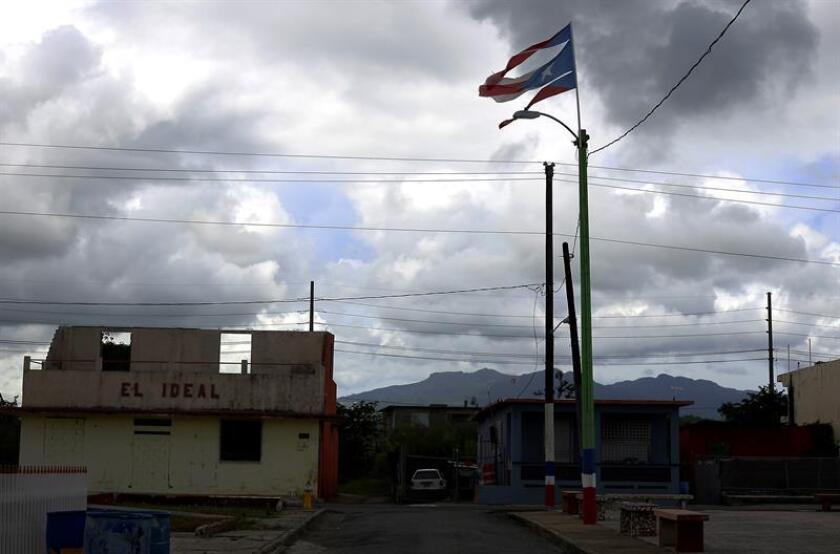 Fotografía del 18 de septiembre 2018, donde se muestra una bandera rota de Puerto Rico ondeando junto a una tienda destrozada por el paso del huracán María, en una de las calles de Humacao (Puerto Rico). EFE/Archivo