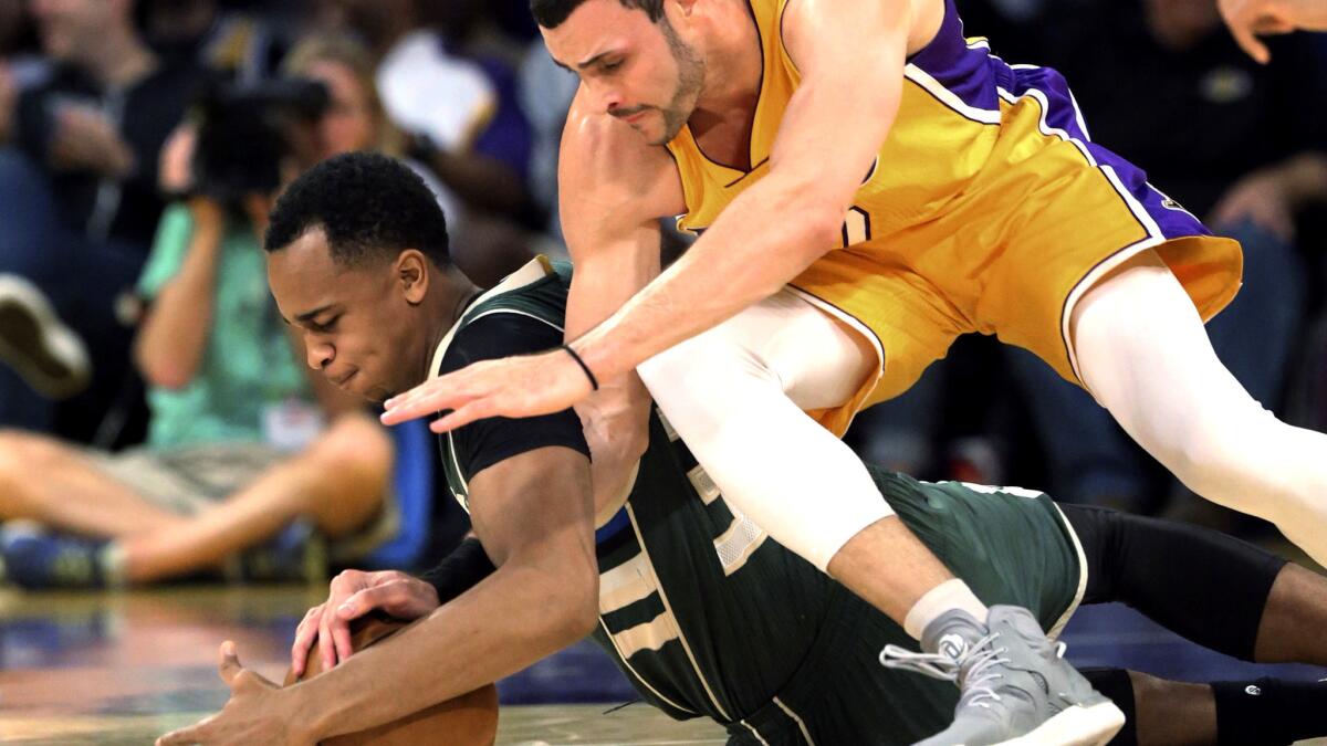 Milwaukee Bucks center John Henson and Lakers forward Larry Nance Jr. chase after a loose ball during the first half Friday night.