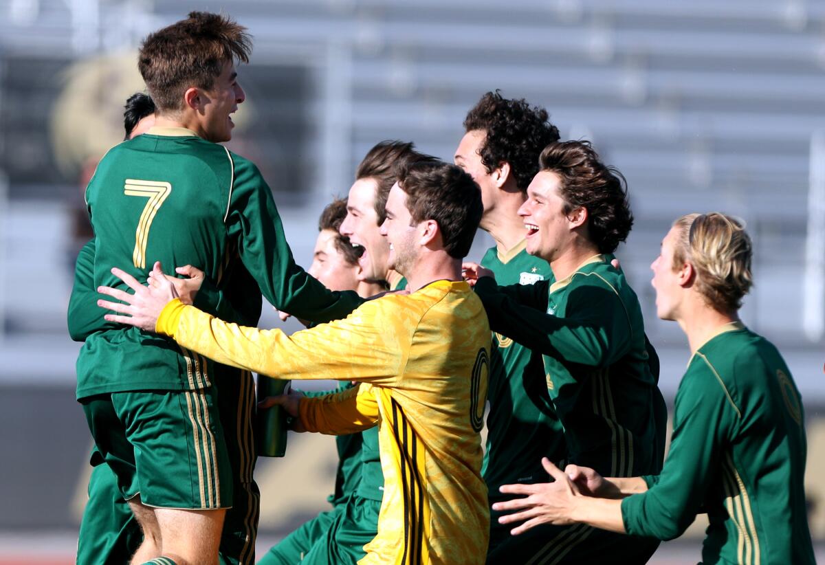 Edison boys' soccer player Armand Pigeon, left, celebrates with the rest of the team after scoring the winning penalty kick after regulation in the Hawks Invitational championship match versus Manhattan Beach Mira Costa at Laguna Hills High on Saturday.