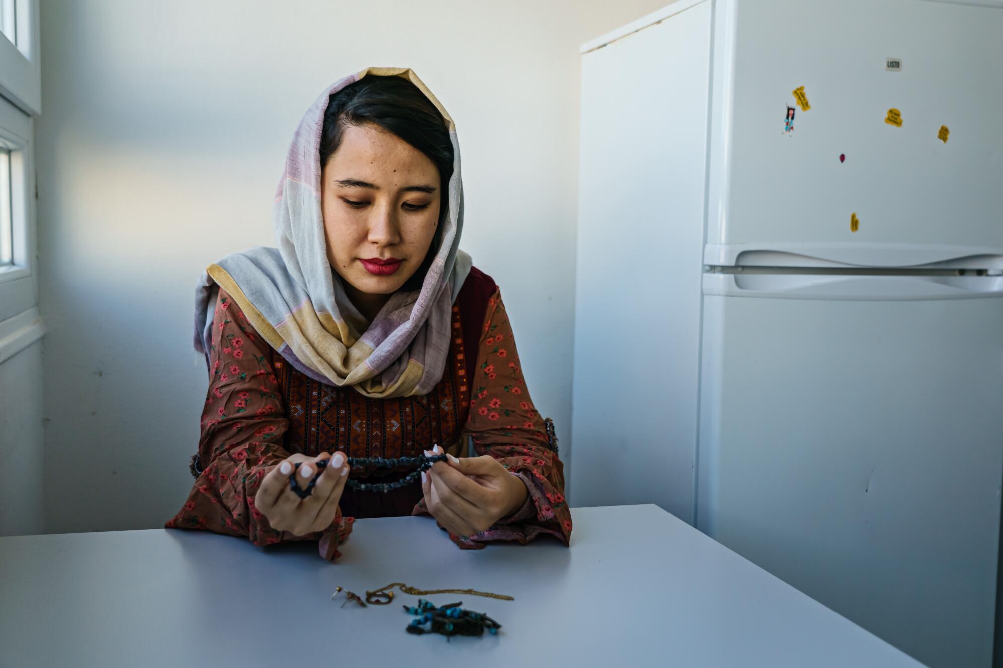 A woman sits at a table and looks at jewelry.