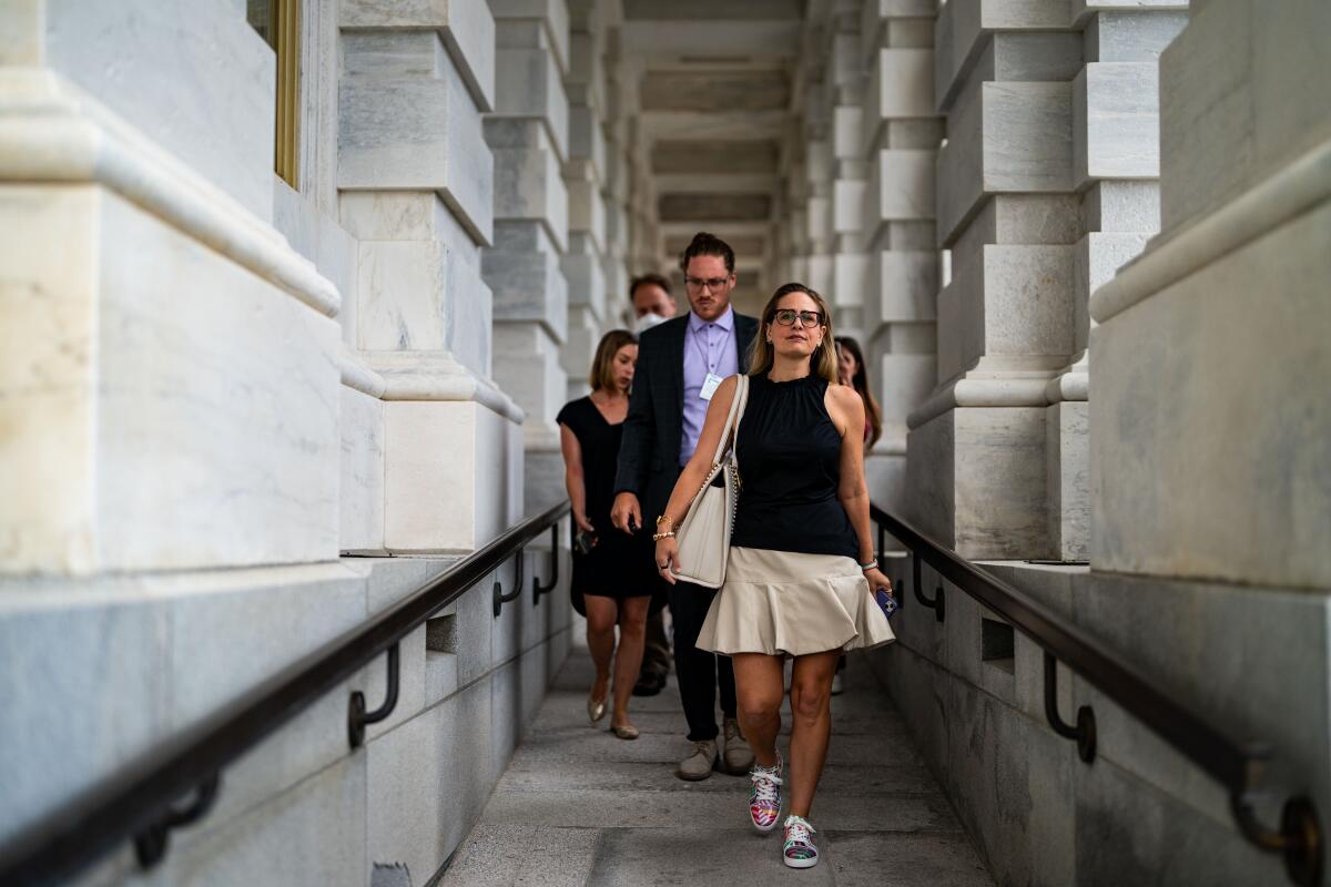 Sen. Kyrsten Sinema walks down a ramp.