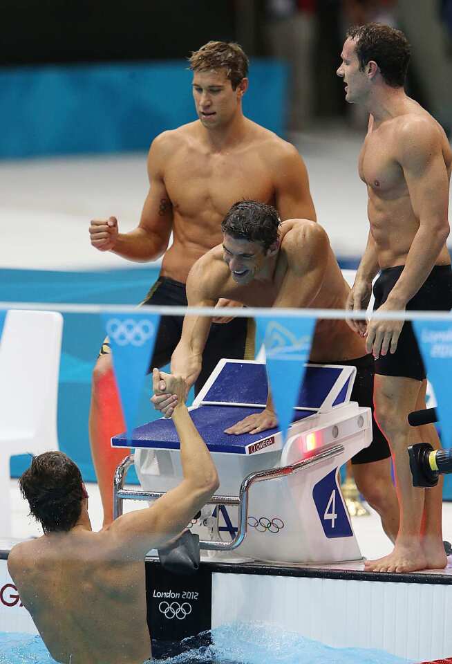Michael Phelps reaches into the pool to congratulate teammate Nathan Adrian who swam the last leg of the men's 4x100 medley relay to win the gold medal. Matt Grevers and Brendan Hansen also swam in the relay.