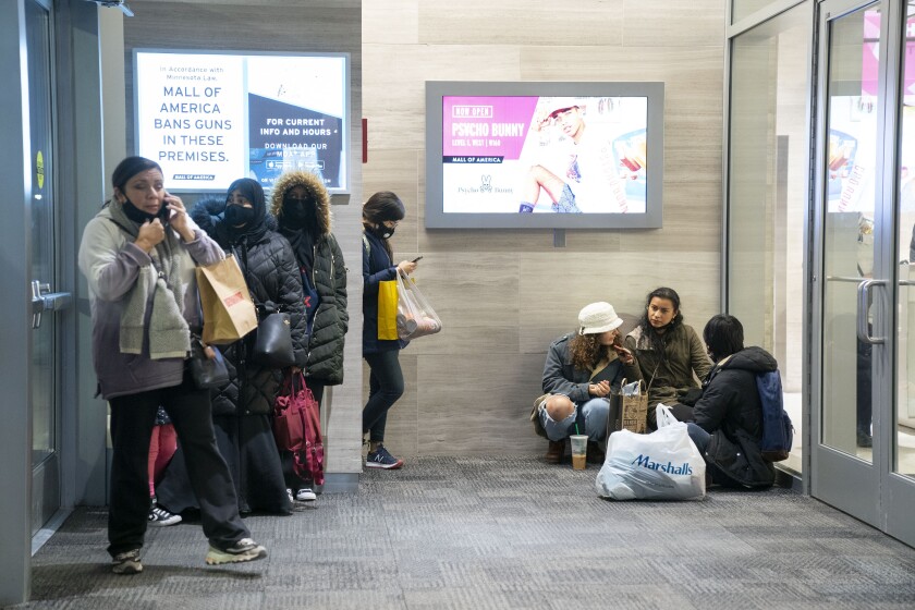 People wait near an exit to be picked up from the Mall of America following a shooting, Friday, Dec. 31, 2021, in Bloomington, Minn. Two people were shot and wounded following an apparent altercation at the Mall of America Friday, sending New Year's Eve shoppers scrambling for safety and placing the Minneapolis mall on temporary lockdown, authorities said. (Alex Kormann/Star Tribune via AP)