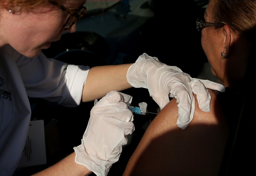 A woman receives a flu vaccine during a drive-thru flu shot clinic in San Pablo, Calif., last November.