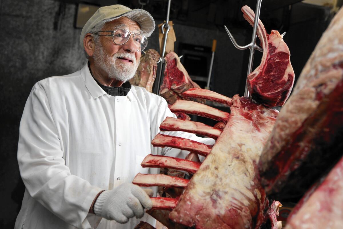Harvey Gussman, who for six decades has provided cuts of meat to a who's who of Los Angeles' culinary scene, checks on a prime rib at his Miracle Mile shop, Harvey's Guss Meat Co.
