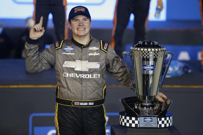 Sheldon Creed stands next to the season champion's trophy after winning the NASCAR Truck Series race at Phoenix.