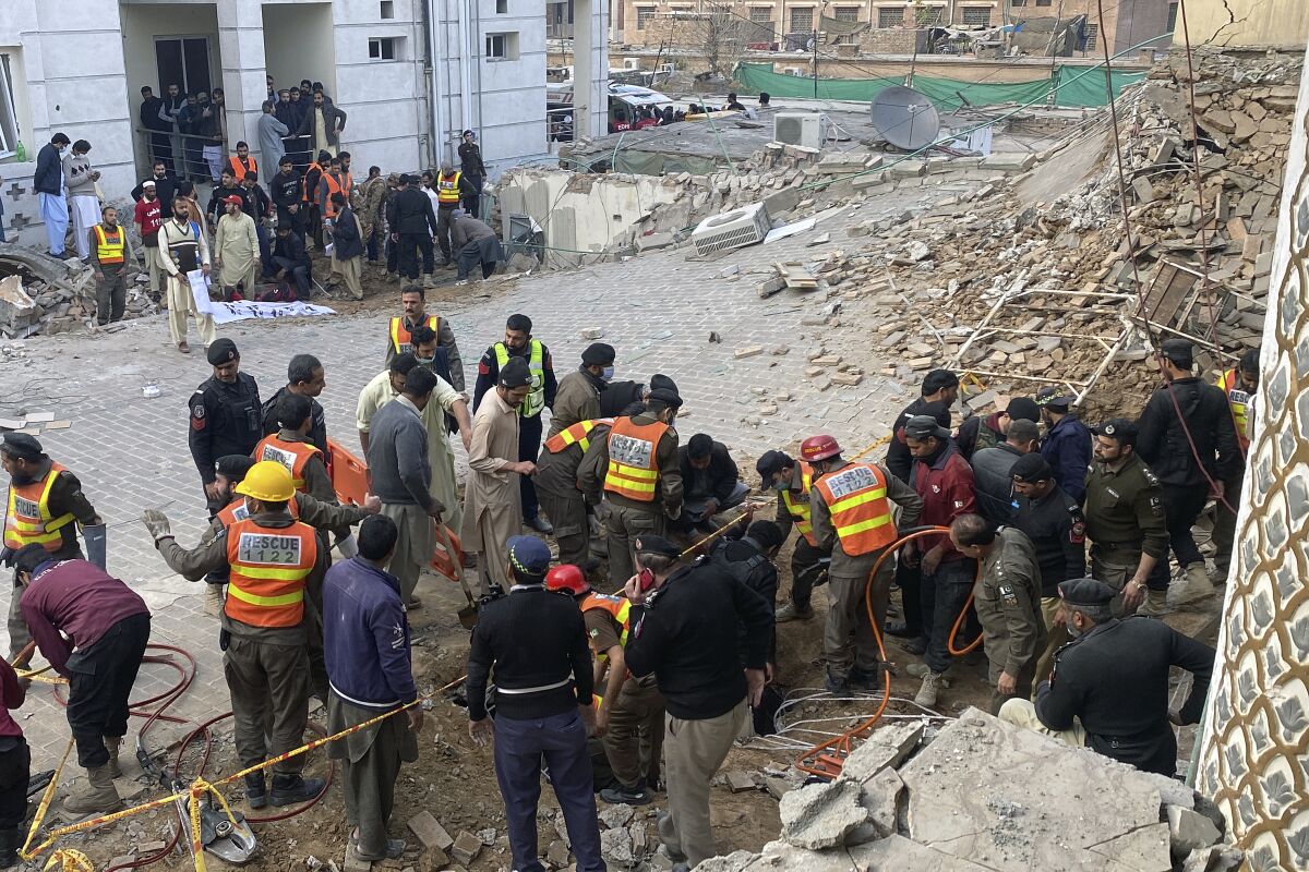 Agentes de seguridad y rescatistas buscan cuerpos en el lugar de un ataque suicida en Peshawar, Pakistán,