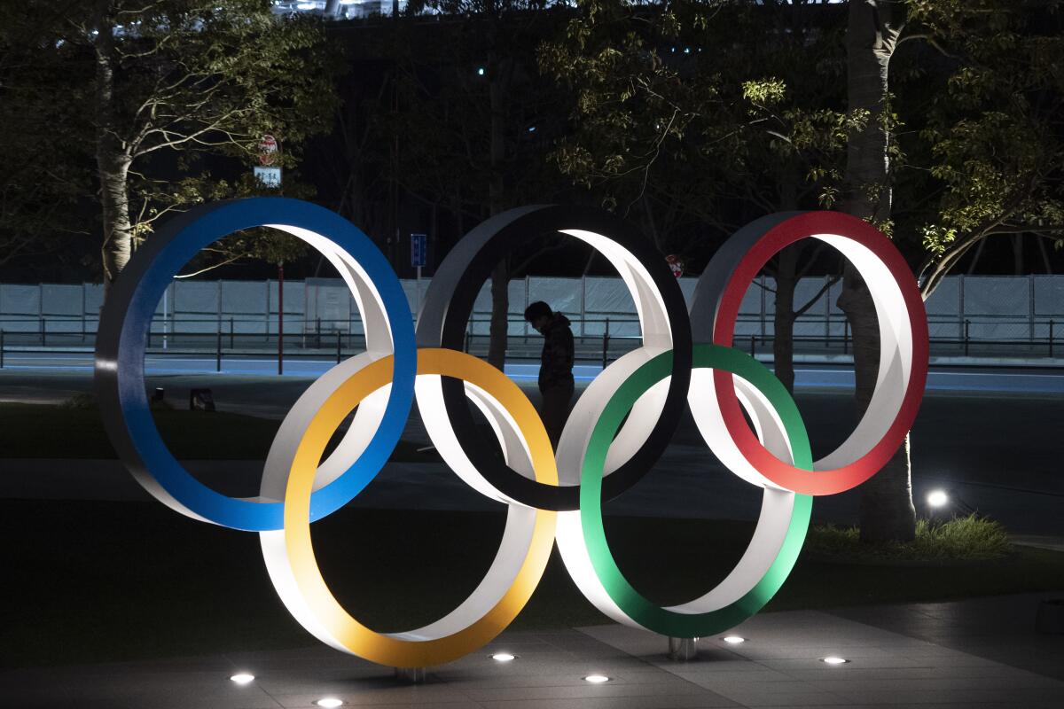 ARCHIVO - En esta foto del 24 de marzo de 2020, un individuo camina cerca de los anillos olímpicos cerca del Estadio Nacional de Tokio. (AP Foto/Jae C. Hong, archivo)