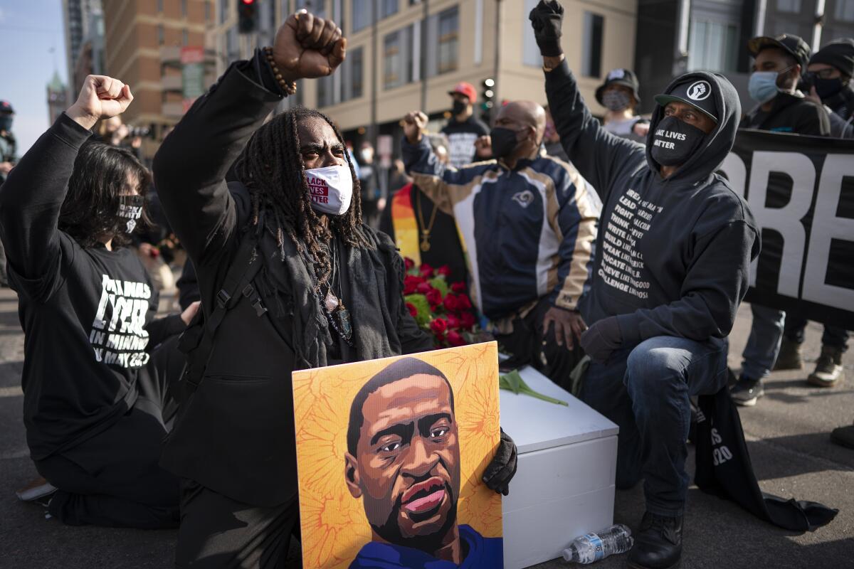 Cortez Rice, left, of Minneapolis, sits with others in the middle of Hennepin Avenue on Sunday, March 7, 2021, in Minneapolis, Minn., to mourn the death of George Floyd a day before jury selection is set to begin in the trial of former Minneapolis officer Derek Chauvin, who is charged in Floyd's death. (Jerry Holt/Star Tribune via AP)