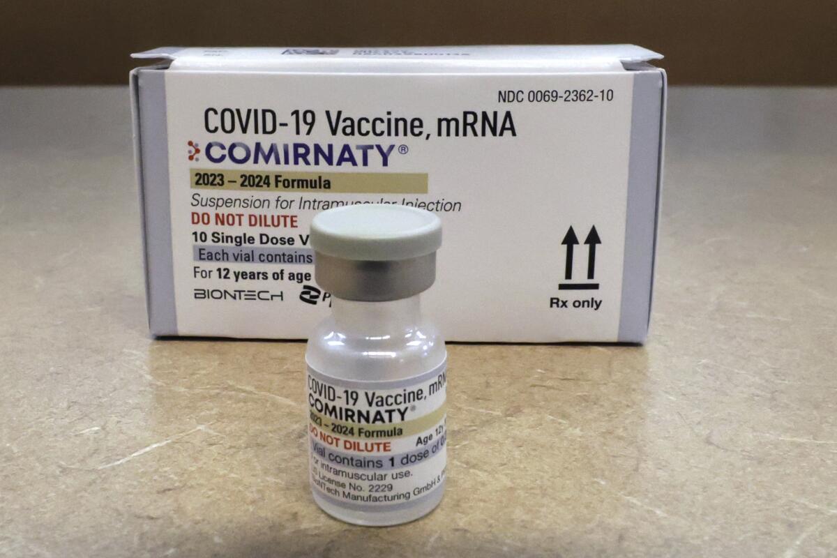 A vial and box of the Comirnaty COVID vaccine on a table 