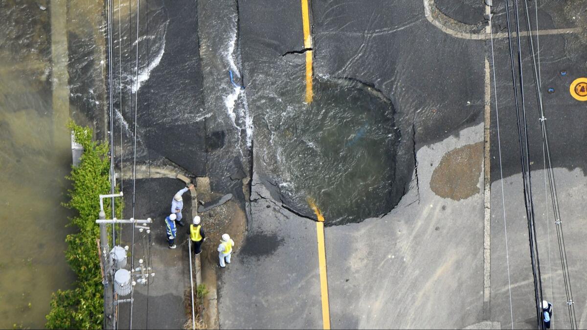 Water from damaged mains floods out from a crack in the road following an earthquake in Osaka, Japan, on June 18.