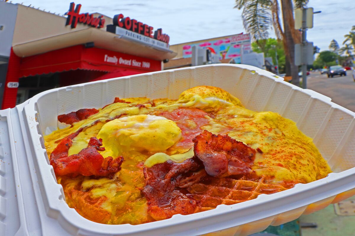 Staying open only for takeout or curbside pickup during the coronavirus crisis, Harry's Coffee Shop in La Jolla is still serving its signature-and-famous breakfast delicacy, "The B.W. Benny": A golden brown waffle is made with bacon slices both inside and on top, along with being covered with grilled ham, poached eggs; and smothered with hollandaise sauce and warm syrup.