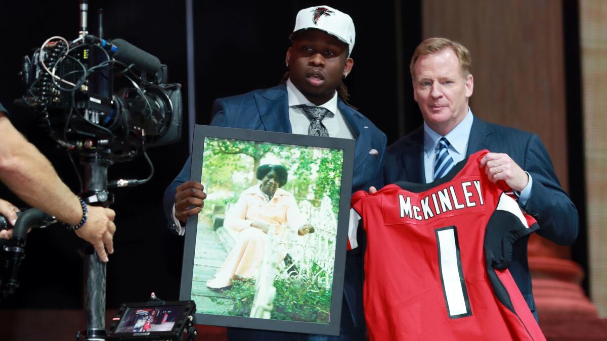 Atlanta Falcons draft pick Takkarist McKinley holds a photo of his late grandmother while posing with NFL Commissioner Roger Goodell on Thursday.