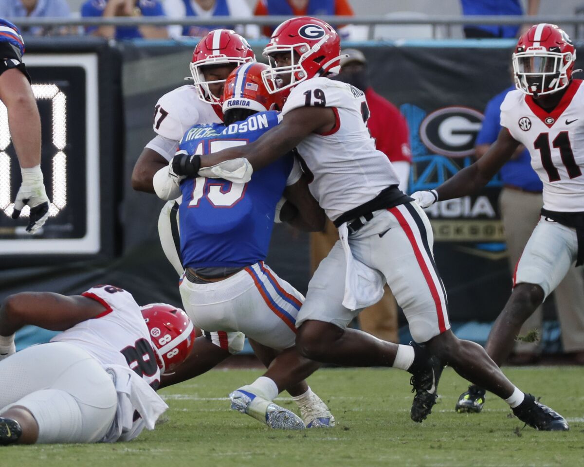 Florida quarterback Anthony Richardson (15) is taken down by Georgia linebacker Nakobe Dean (17) and linebacker Adam Anderson (19) during the second half of an NCAA college football game Saturday, Oct. 30, 2021, in Jacksonville, Fla. (Bob Andres/Atlanta Journal-Constitution via AP)