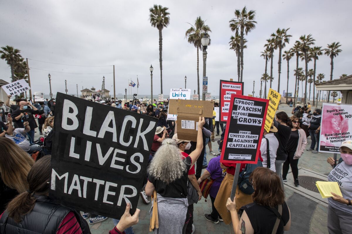 Protesters hold signs during a rally Sunday in Huntington Beach