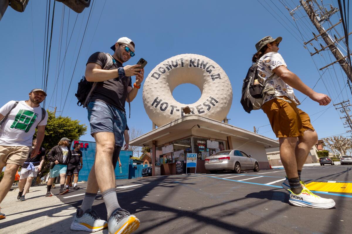 A low-angle photo of people walking past a Donut King.