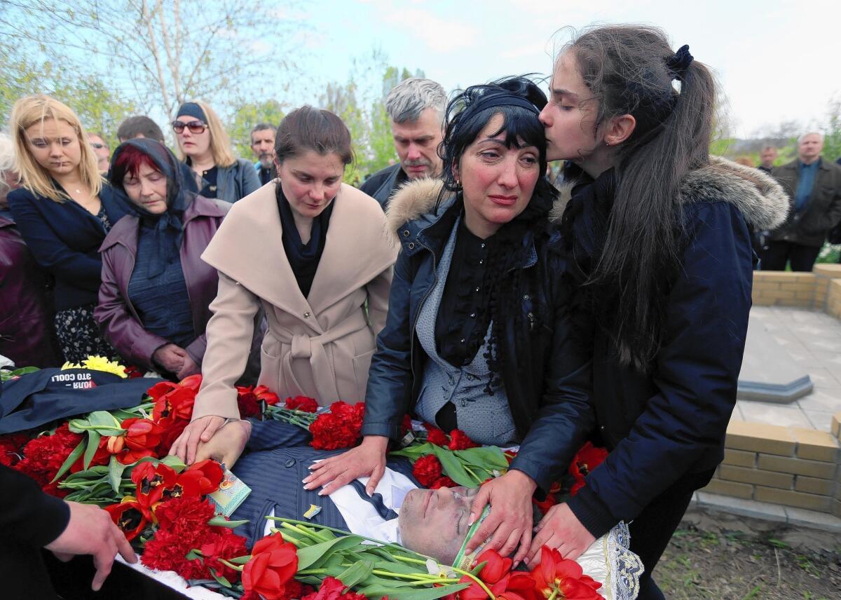 Yelena Rybak is comforted by her daughter at the funeral of her husband, Volodymyr, in Horlivka, Ukraine.