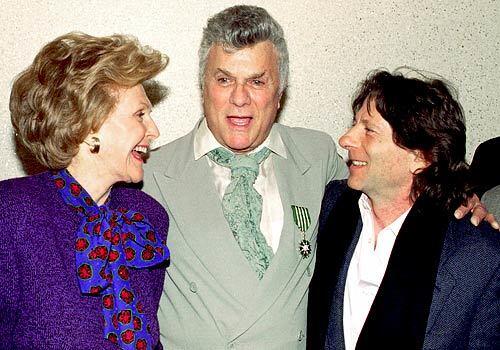 Tony Curtis is congratulated by U.S. Ambassador to France Pamela Harriman, left, and film director Roman Polanski, on the occasion of being knighted Chevalier of the Order of Arts and Letters in a ceremony in Paris in 1995. See full story