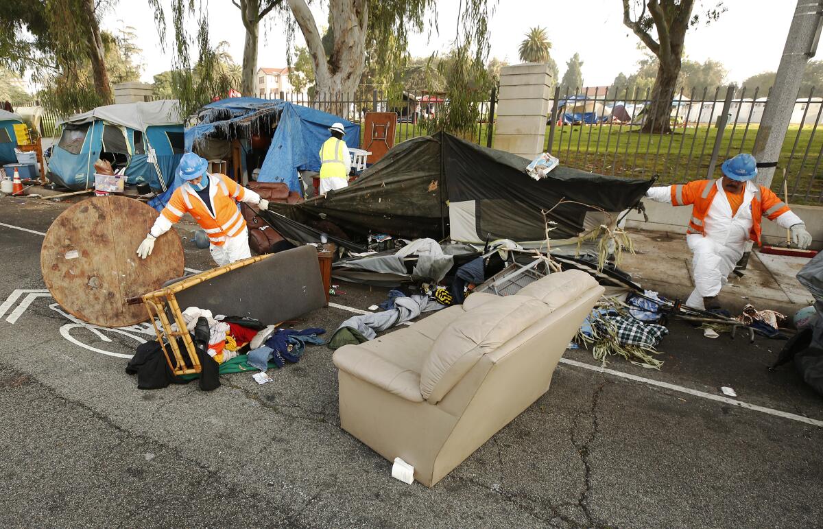 A cleanup crew dismantles tents in a homeless encampment.
