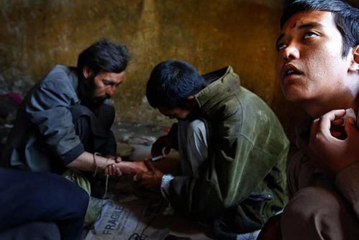 Anwar, center, an "expert shooter," injects a mixture of heroin and water into a vein of a man called Hussein at the abandoned Russian Cultural Center in downtown Kabul. Jaffer, at right, was just injected in the neck.