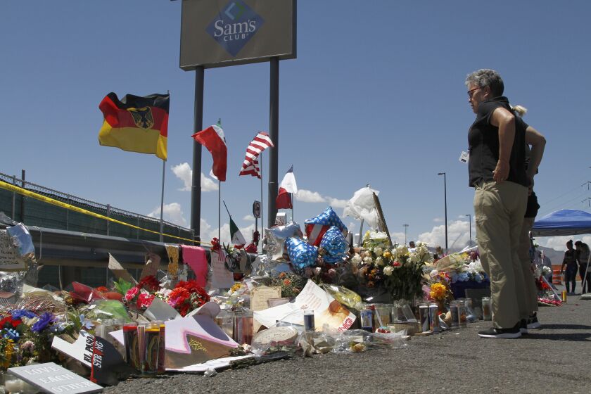 FILE - Mourners visit a makeshift memorial on Aug. 12, 2019, near the Walmart in El Paso, Texas, where people were killed in a mass shooting. On Monday, Nov. 28, 2022, a Texas prosecutor, facing mounting criticism over the handling of the 2019 Walmart mass shooting in El Paso, resigned after the county took the extraordinary step of moving to remove her from elected office. (AP Photo/Cedar Attanasio, File)