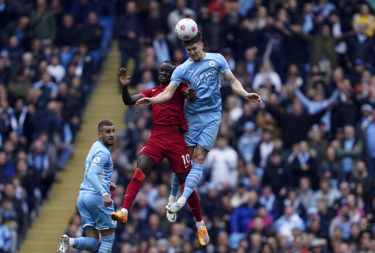 Liverpool's Sadio Mane, left, duels for the ball with Manchester City's John Stones during the English Premier League soccer match between Manchester City and Liverpool, at the Etihad stadium in Manchester, England, Sunday, April 10, 2022. (AP Photo/Jon Super)