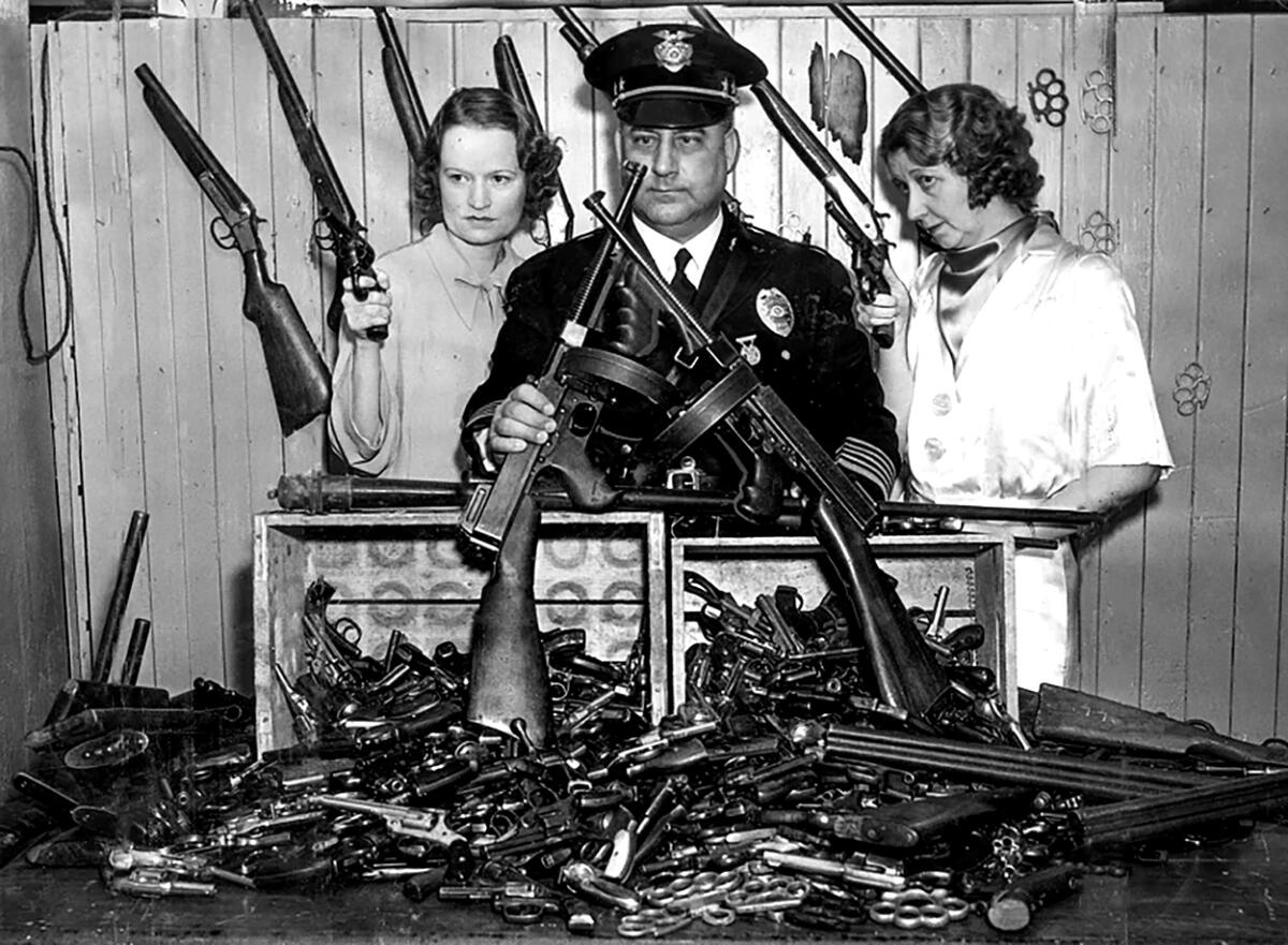 Chief of Police James Davis and two female officers, all holding confiscated guns