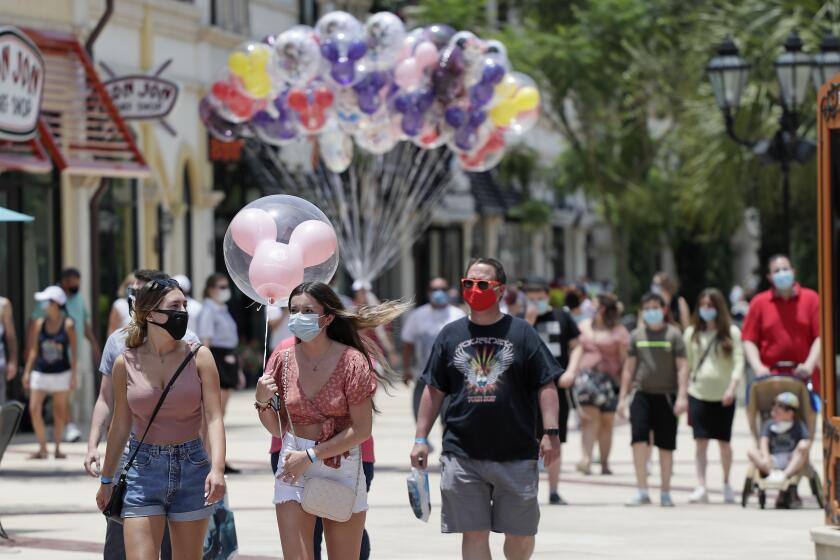 ARCHIVO - En imagen de archivo del 16 de junio de 2020, visitantes usan mascarillas de forma obligatoria a causa del coronavirus durante un recorrido por el complejo de tiendas, restaurantes y centros de entretenimiento Disney Springs en Lake Buena Vista, Florida. (AP Foto/John Raoux, archivo)