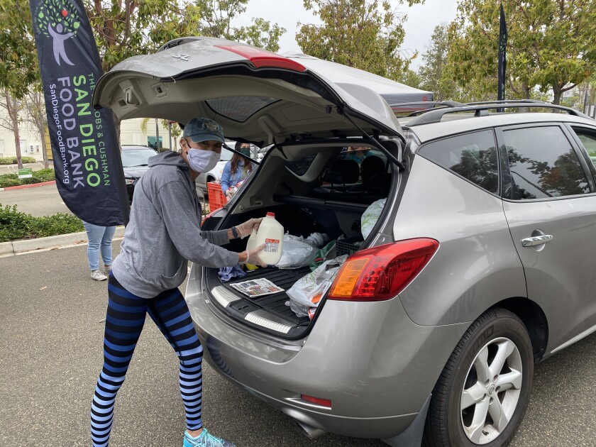 A volunteer with the San Diego Food Bank loads groceries into a car during a food distribution event.